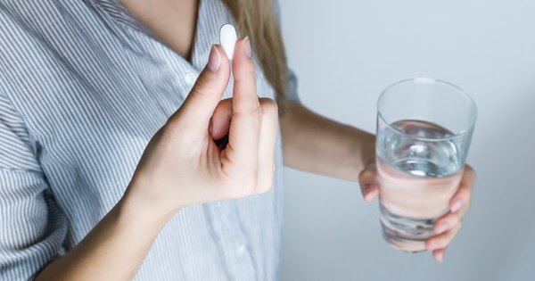 Hashimoto Behandlung - Frau mit Glas Wasser und Tablette