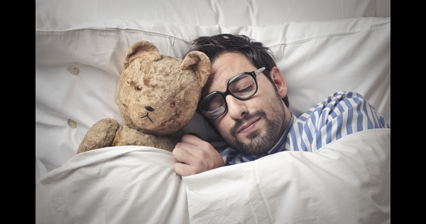 Gesunder Schlaf - Mann kuschelt mit seinem Teddy und schläft